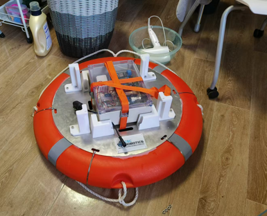 Built float with an orange ring, aluminum platform, pale mounts, and strapped electronics enclosure